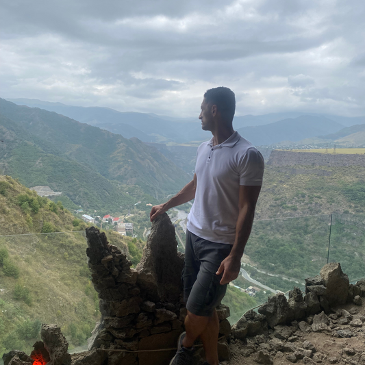 Edmond Margaryan standing atop a mountain in Armenia, gazing into the distance, symbolizing the beginning of a journey of adventure and acts of kindness.